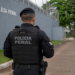 Policial penal de costas em frente a unidade prisional.
