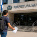 Candidato caminha em direção à Prefeitura Municipal segurando documento de concurso público.