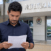 Candidato lê documento de concurso público em frente à Prefeitura Municipal.