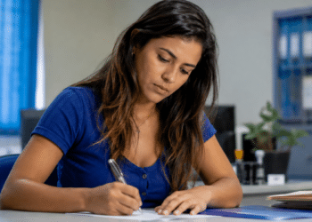 Candidata escreve em documento durante preparação para concurso público da prefeitura.