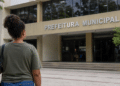 Pessoa em frente à prefeitura municipal simbolizando inscrição em concurso da Prefeitura com salário de até R$ 5 mil.