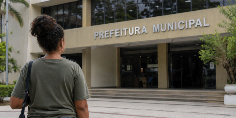 Pessoa em frente à prefeitura municipal simbolizando inscrição em concurso da Prefeitura com salário de até R$ 5 mil.