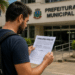 Homem lendo edital de concurso público em frente à Prefeitura Municipal.