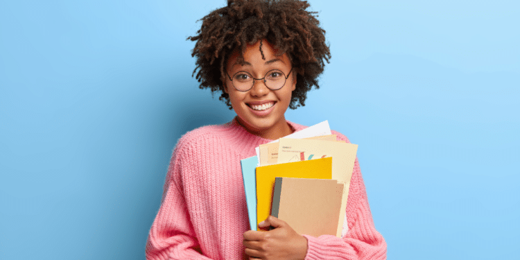 Jovem segurando livros e documentos para estudos de concursos públicos.