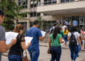 Pessoas caminhando em direção à prefeitura municipal segurando documentos de concurso público.