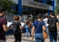 Candidatos com documentos de concurso caminham em direção a uma Câmara Municipal.