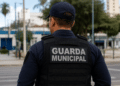 Guarda municipal fardado de costas em área urbana simbolizando segurança pública.