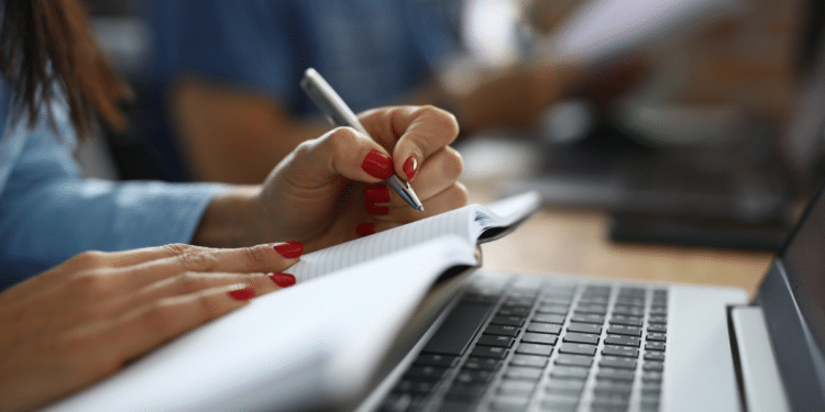 Pessoa fazendo anotações em caderno ao lado de um notebook, representando concursos públicos em SP com inscrições abertas..