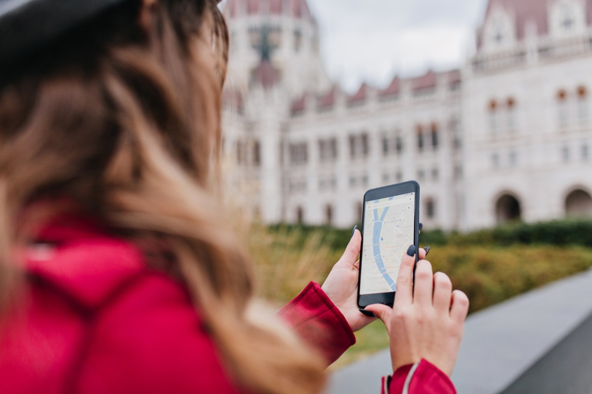 Mulher segura o celular com um mapa aberto na tela em frente a um edifício histórico