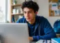 Jovem estudante brasileiro consultando vagas do Sisu+ 2026 em notebook durante rotina de estudos
