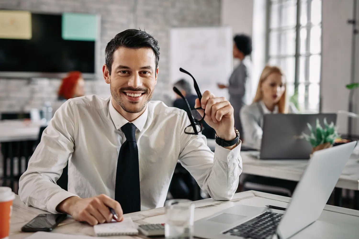 Empreendedorismo contábil e novas oportunidades profissionais Profissional de contabilidade em ambiente corporativo sorrindo enquanto trabalha com documentos e notebook.
