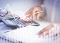Analista financeiro e contador avaliando gráficos de desempenho em tela digital, representando gestão e crescimento de pequenas empresas.