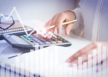 Analista financeiro e contador avaliando gráficos de desempenho em tela digital, representando gestão e crescimento de pequenas empresas.