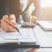 Profissional analisando documentos e gráficos financeiros em ambiente de escritório, representando planejamento para abertura de negócio contábil.