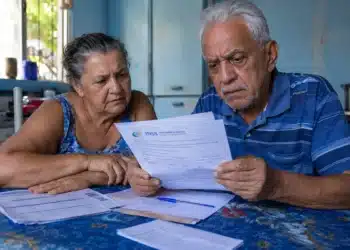 Aposentado e pensionista analisando documentos do INSS, representando a contestação de descontos indevidos no benefício até 20 de junho.