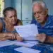 Aposentado e pensionista analisando documentos do INSS, representando a contestação de descontos indevidos no benefício até 20 de junho.