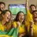 Torcedores brasileiros comemoram em casa durante jogo da Seleção na Copa do Mundo de 2026