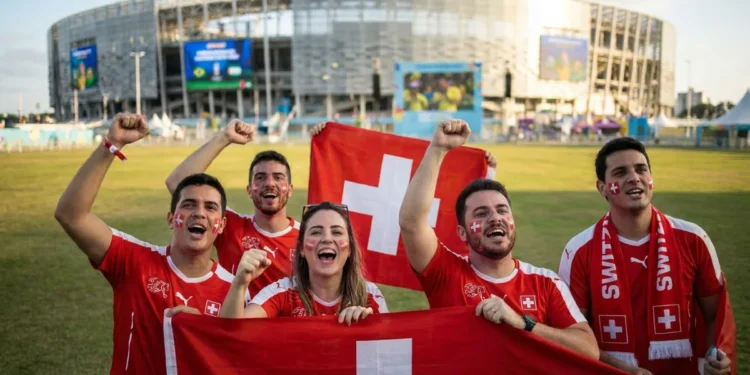 Torcedores da Suíça celebram com bandeiras durante a Copa do Mundo 2026, representando a segunda rodada da fase de grupos