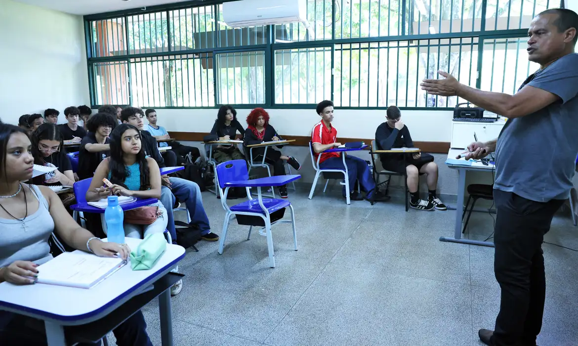 Importância e benefícios do exame para os professores Professor leciona em sala de aula representando a carreira avaliada pela Prova Nacional Docente