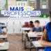 Professora sorridente de braços cruzados em sala com alunos ao fundo, representando os cursos do programa Mais Professores para o Brasil