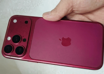 Mão segurando iPhone na cor vinho/burgundy com módulo de câmera tripla e logo da Apple visível.