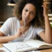 Mulher com expressão pensativa diante de um caderno com dúvida sobre o uso correto de fase ou faze.