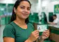 Mulher em unidade de atendimento segurando documento de identidade, representando a ação de emissão da segunda via do RG