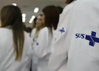 Profissionais da saúde com jaleco do SUS durante ambiente de formação e residência médica.