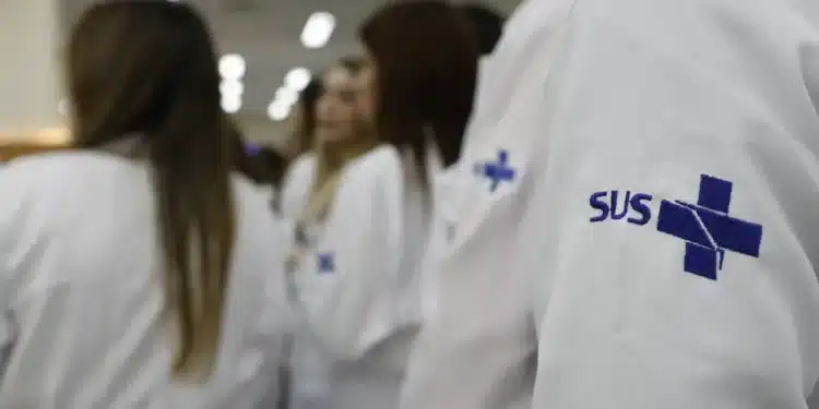 Profissionais da saúde com jaleco do SUS durante ambiente de formação e residência médica.