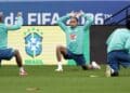 Jogadores da seleção brasileira fazem alongamento em treino diante de painel da Copa do Mundo FIFA 2026