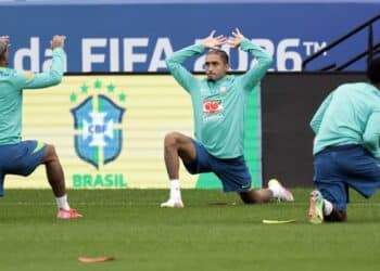 Jogadores da seleção brasileira fazem alongamento em treino diante de painel da Copa do Mundo FIFA 2026
