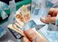 Mão segurando dinheiro em reais ilustrando liberação de saque do FGTS no valor de R$ 6.220 a partir desta quinta-feira, 18 de junho.