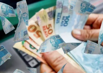 Mão segurando dinheiro em reais ilustrando liberação de saque do FGTS no valor de R$ 6.220 a partir desta quinta-feira, 18 de junho.