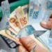 Mão segurando dinheiro em reais ilustrando liberação de saque do FGTS no valor de R$ 6.220 a partir desta quinta-feira, 18 de junho.