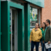 Grupo de pessoas em frente à porta de uma agência bancária, com bandeiras do Brasil na rua