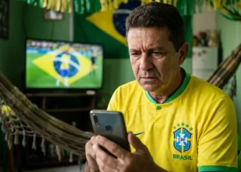 Torcedor brasileiro acompanha notícias no celular durante clima de alerta para golpes ligados à Copa de 2026.