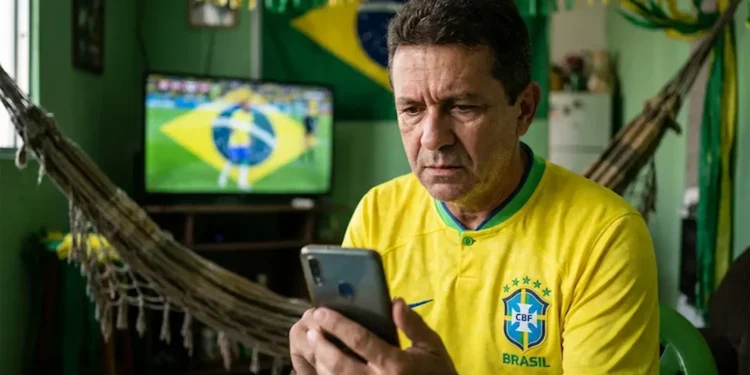 Torcedor brasileiro acompanha notícias no celular durante clima de alerta para golpes ligados à Copa de 2026.