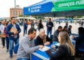 Cidadãos sendo atendidos em tendas do programa Governo na Rua em praça de Porto Alegre, com fila de pessoas aguardando serviços públicos