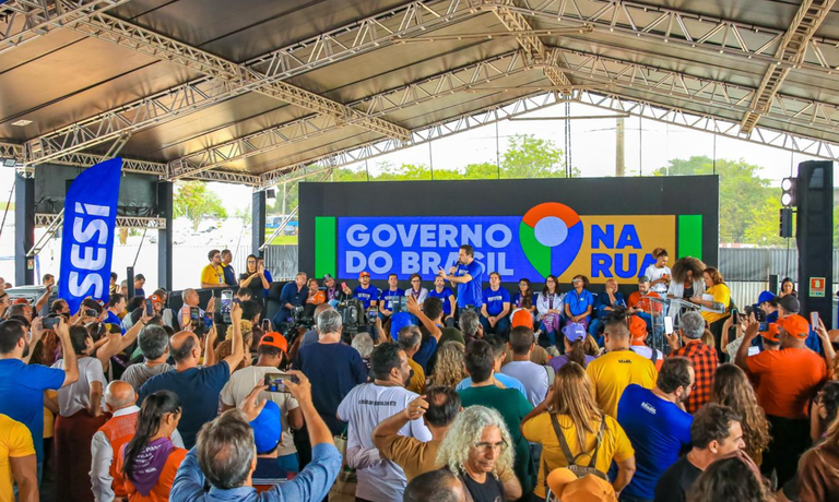 Palco com painel do Governo do Brasil na Rua diante de público em evento