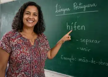 Professora brasileira apontando para o quadro com a palavra “hífen” em sala de aula