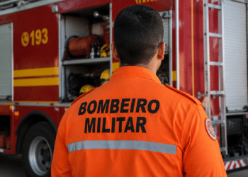 Bombeiro militar visto de costas em frente a viatura do Corpo de Bombeiros durante operação.