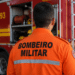 Bombeiro militar visto de costas em frente a viatura do Corpo de Bombeiros durante operação.