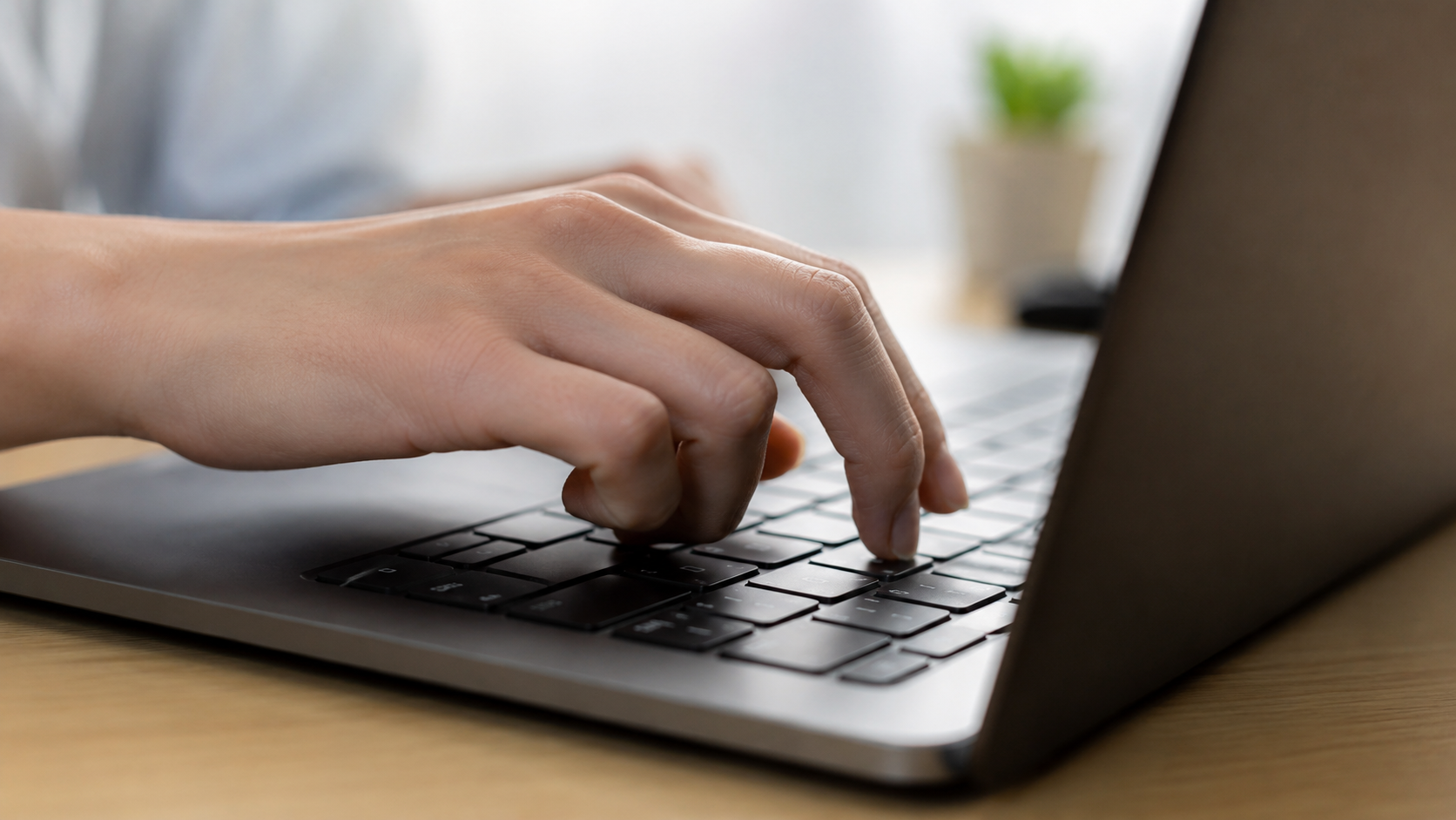 Mão digitando em notebook, representando inscrição online para concurso da Prefeitura de Saquarema-RJ.