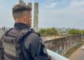 Agente da Polícia Penal de costas observa muro de unidade prisional
