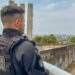 Agente da Polícia Penal de costas observa muro de unidade prisional