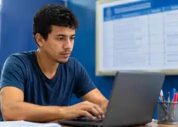Jovem brasileiro utilizando um notebook, representando o período de inscrição prorrogado até 10 de julho.