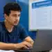 Jovem brasileiro utilizando um notebook, representando o período de inscrição prorrogado até 10 de julho.