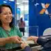 Mulher recebe cédulas de reais durante atendimento bancário, representando o pagamento do INSS de até R$ 8.475,55.