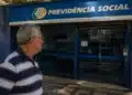 Idoso observando agência do INSS fechada, representando a suspensão de pagamentos de benefícios nesta quinta-feira, 4 de junho.