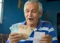 Aposentado brasileiro de cabelos grisalhos segurando cédulas de R$ 100 e R$ 50, olhando com expressão de surpresa, representando o pagamento de R$ 4.500 em 8 de junho.